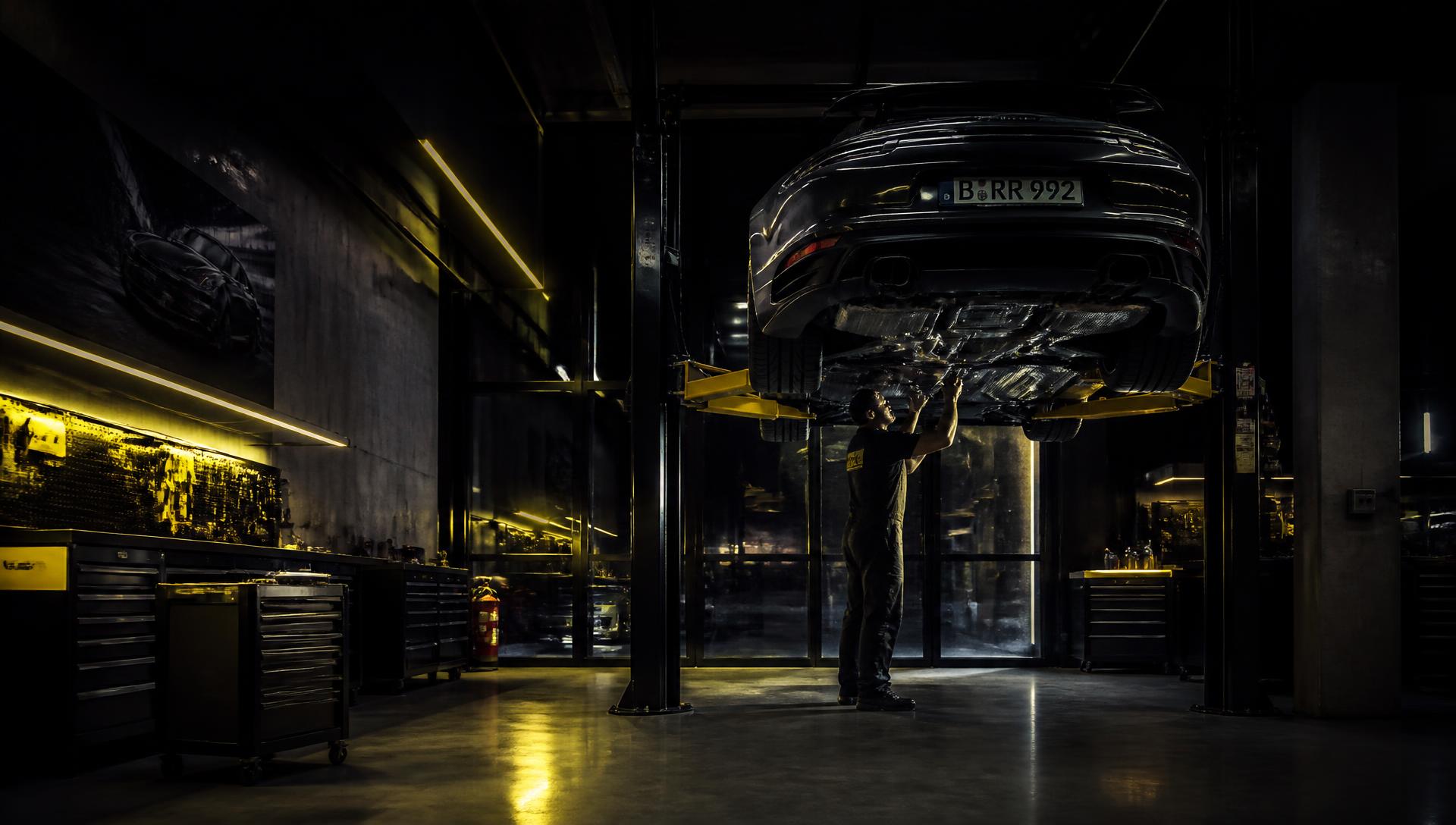 Mechanic working under a car on a ramp in a professional garage workshop